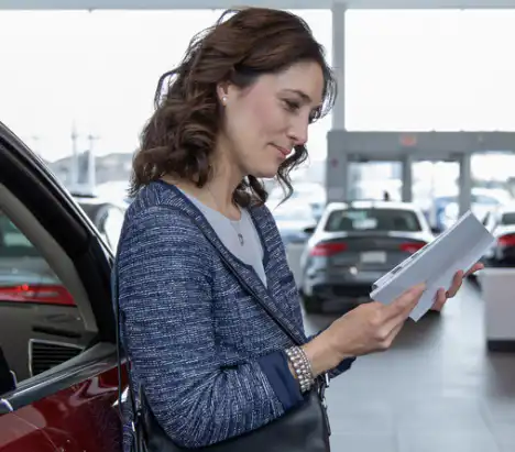 Customer looking at driveaway car insurance documents in a car showroom